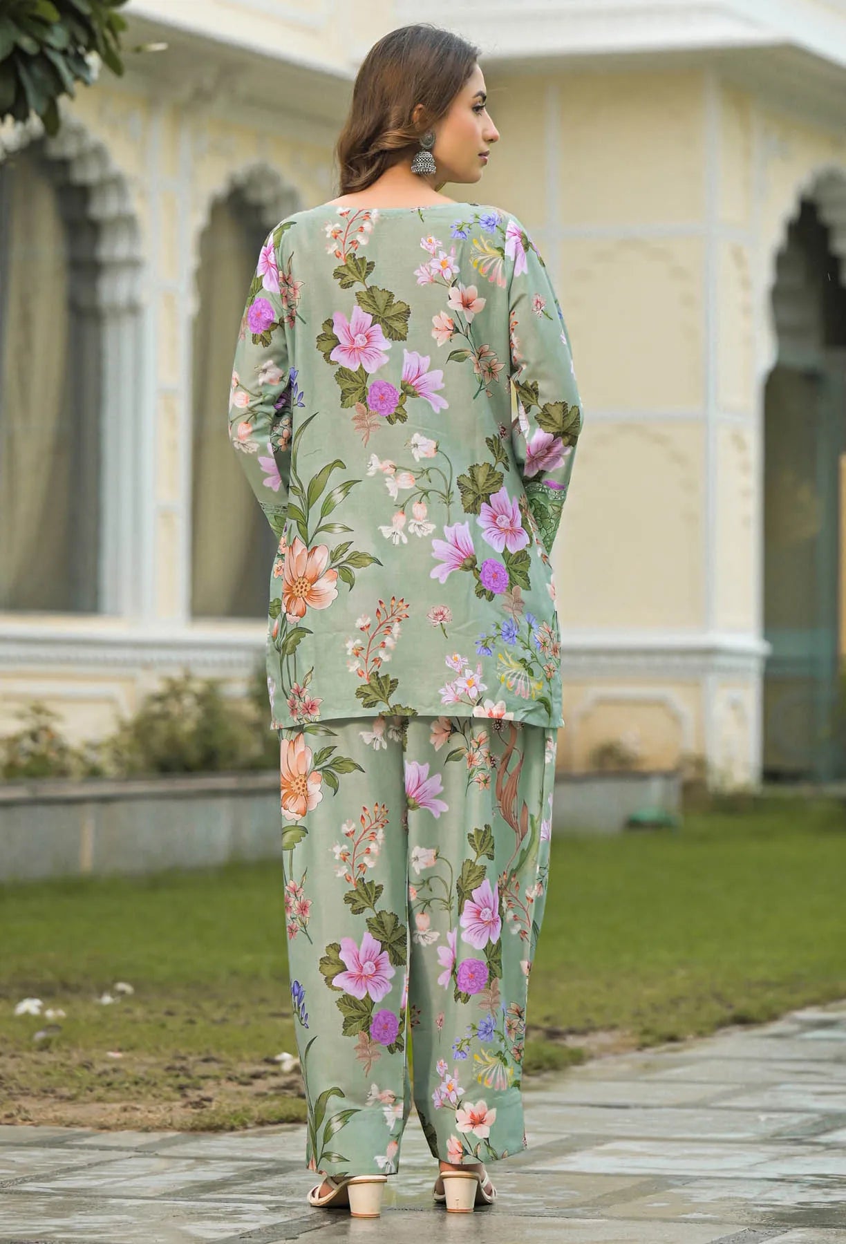 Woman wearing a floral outfit standing outdoors with a building in the background