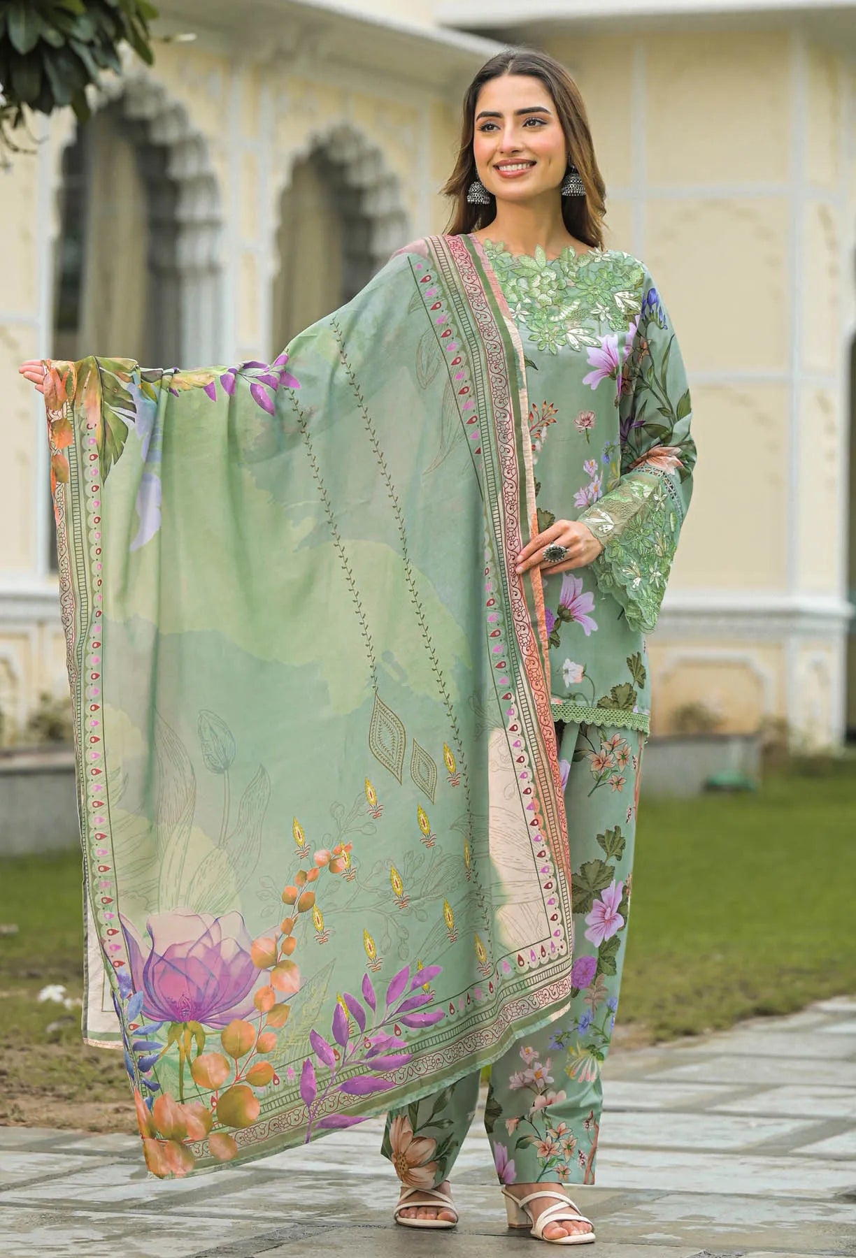 Woman wearing a green floral outfit with a matching dupatta in an outdoor setting.