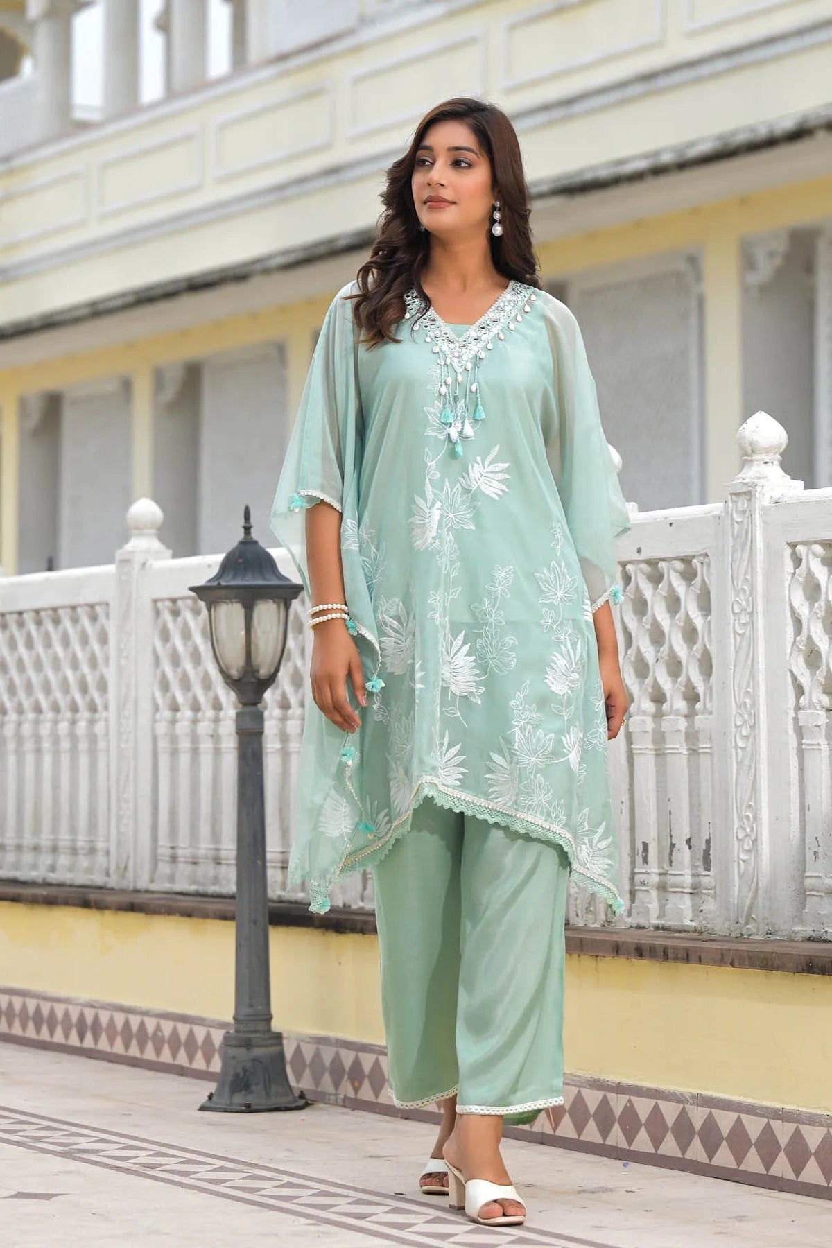 Woman in a light green traditional outfit standing on a balcony.