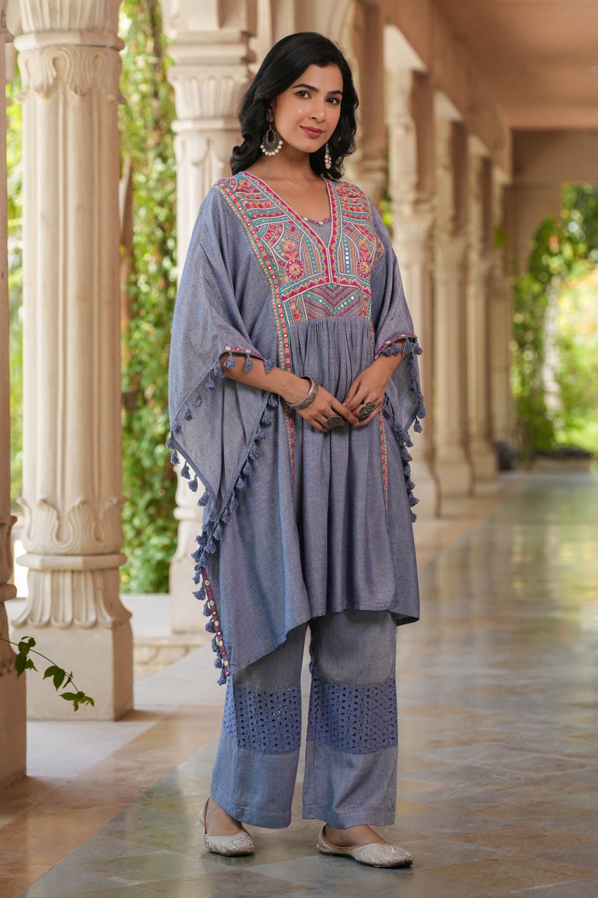 Woman wearing a traditional outfit with intricate patterns in an outdoor setting.
