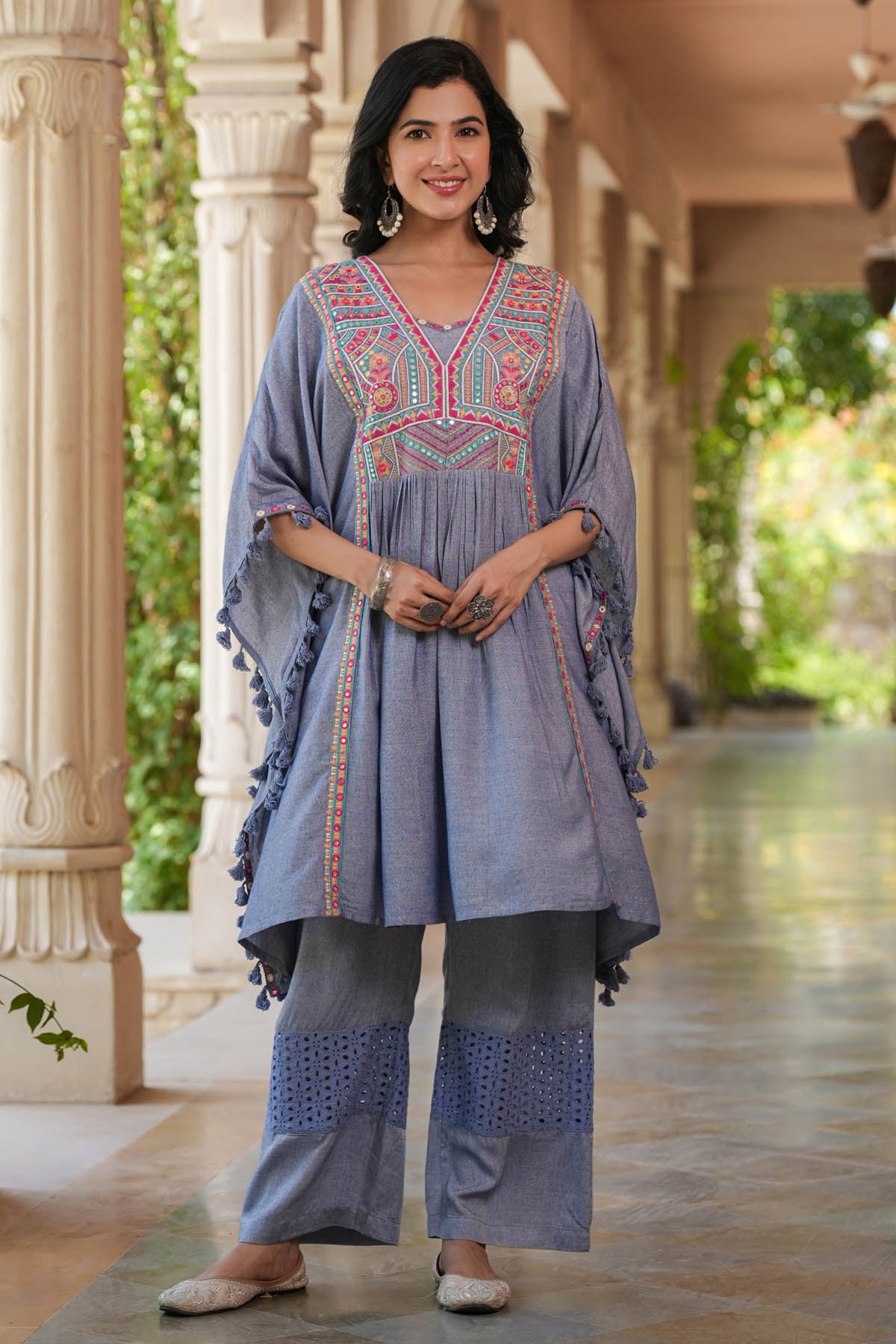 Woman wearing a traditional outfit with intricate embroidery in an outdoor setting.
