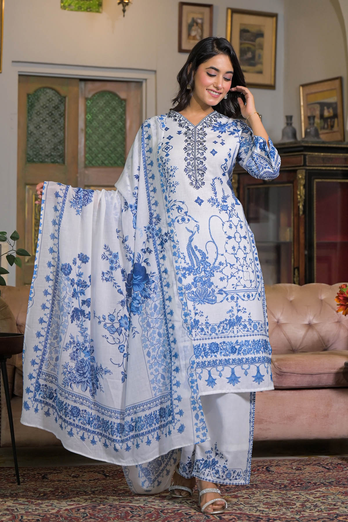Woman wearing a blue and white embroidered outfit in a decorated room.