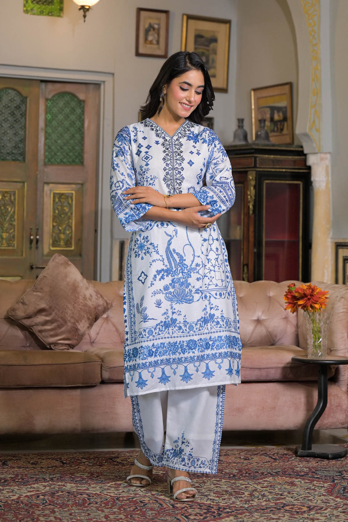 Woman in a blue and white traditional outfit standing in a living room.
