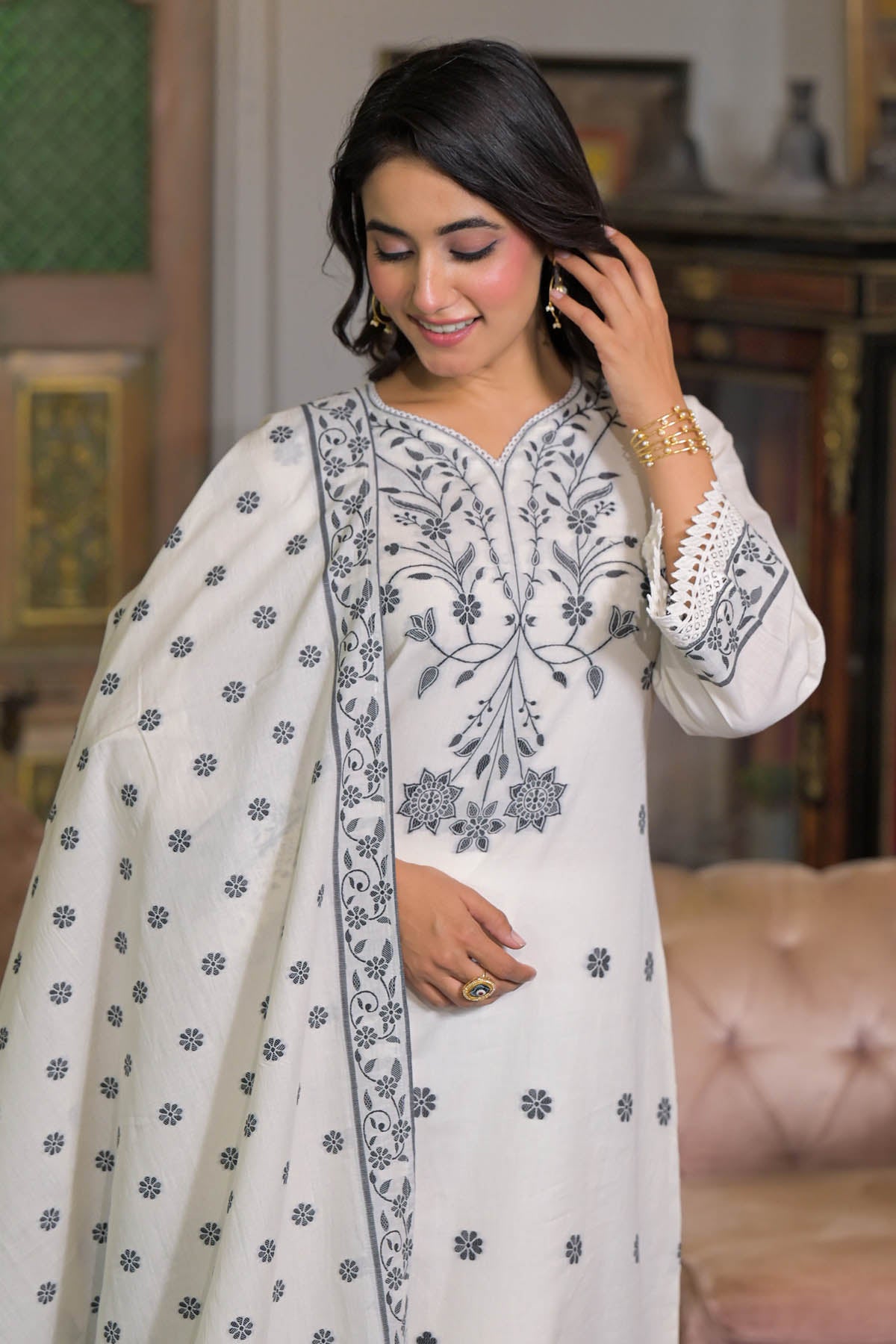 Woman wearing a white embroidered traditional outfit in an indoor setting.