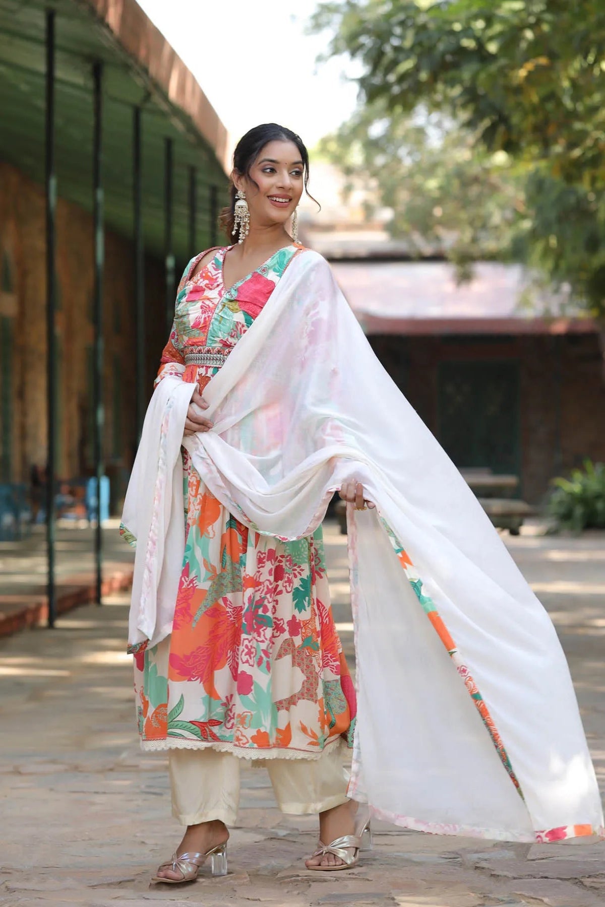Woman in a floral dress with a white dupatta standing outdoors.