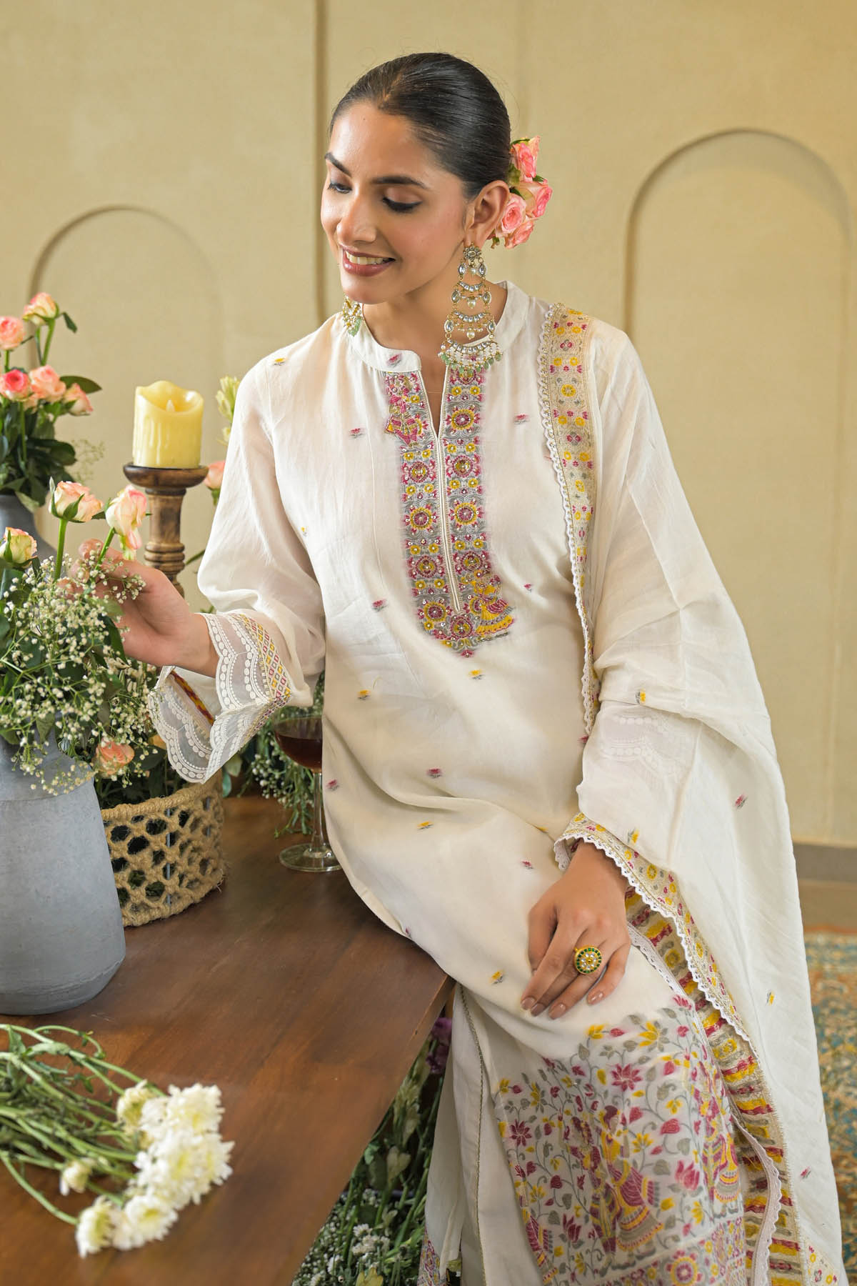 Woman in traditional white embroidered outfit with floral decorations indoors