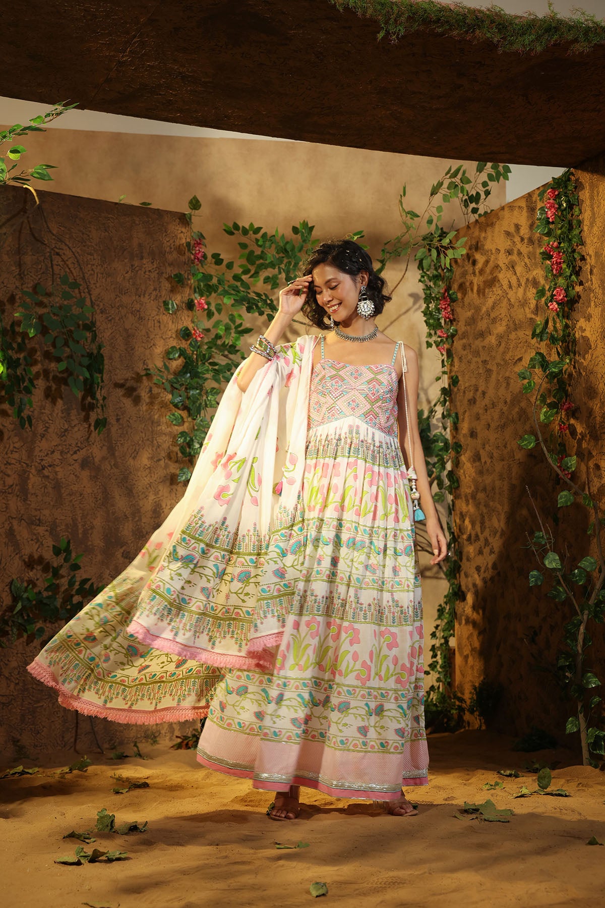 Woman in a traditional outfit with floral patterns against a decorated wall.