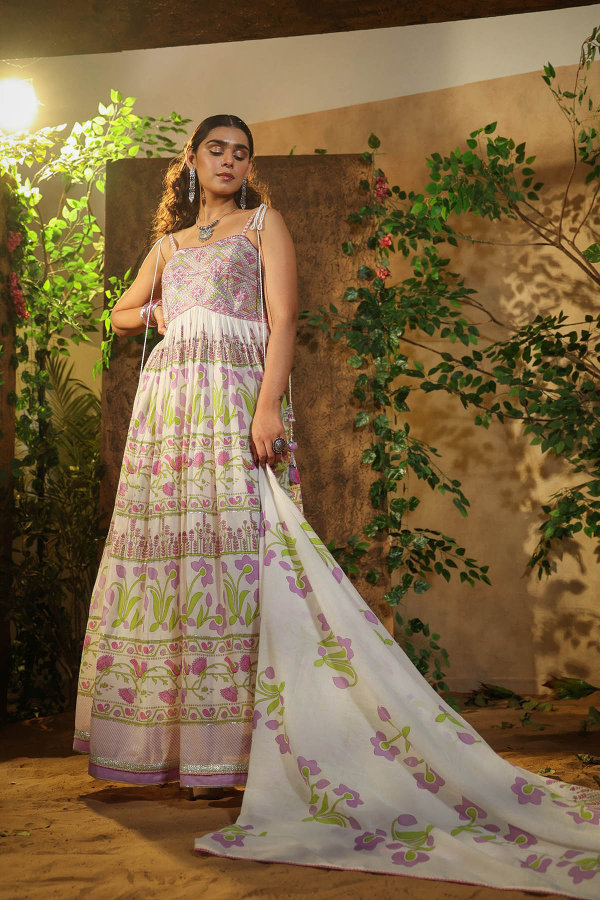 Woman in a floral dress standing in front of a natural background with plants.