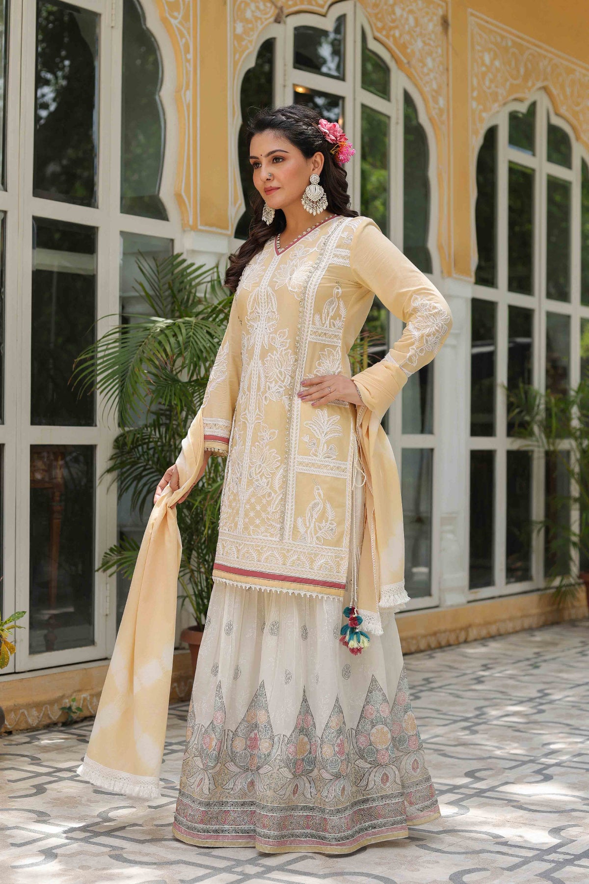 Woman in a traditional outfit standing in front of a decorative building entrance.
