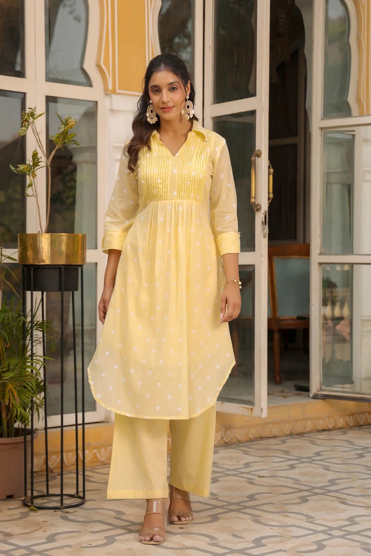 Woman in a yellow traditional outfit standing in front of a glass door.