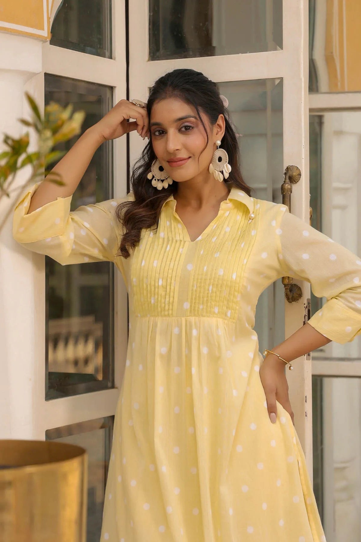 Woman wearing a yellow dress with white polka dots indoors.