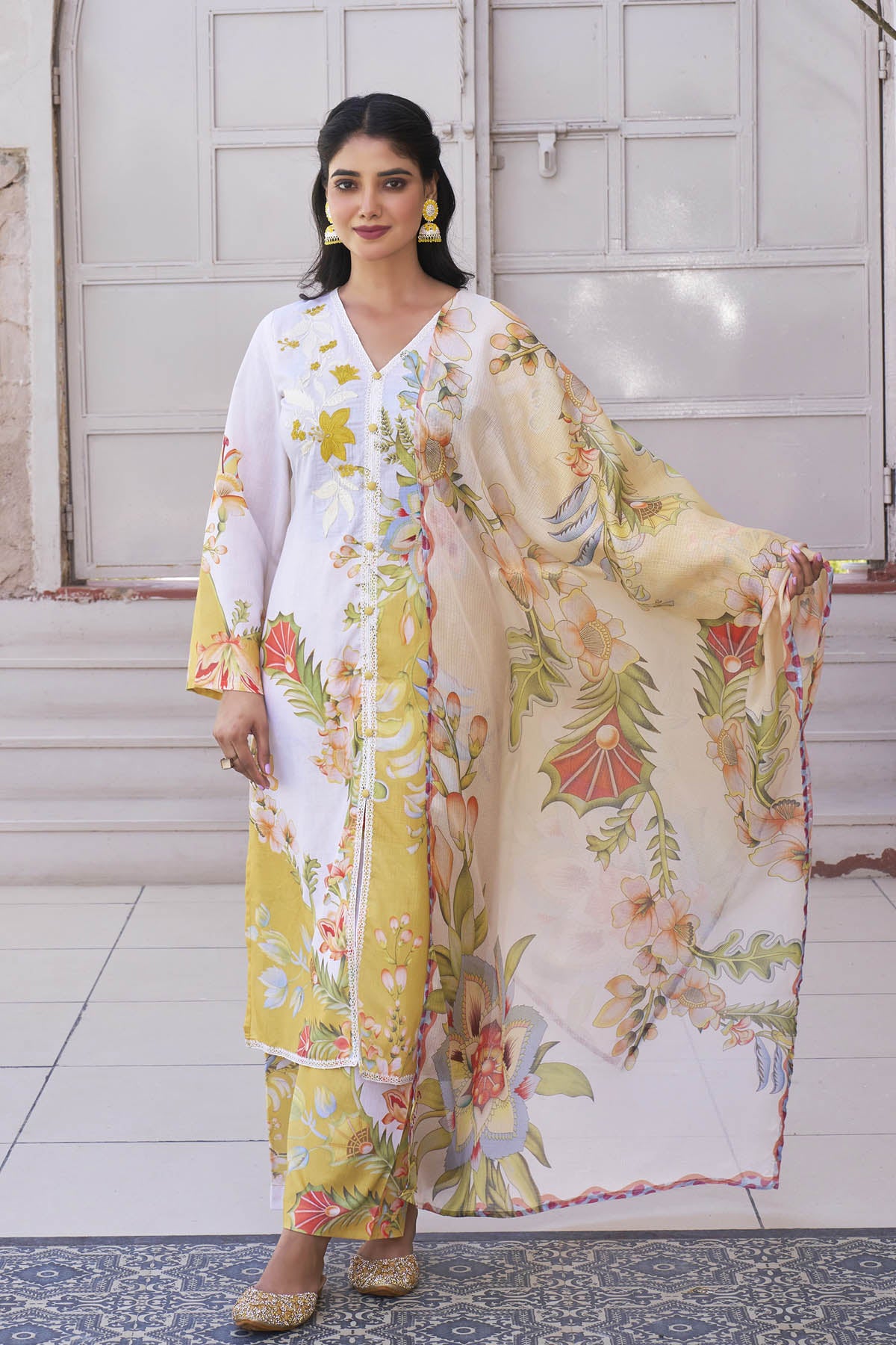 Woman wearing a floral outfit with a large scarf in a room.