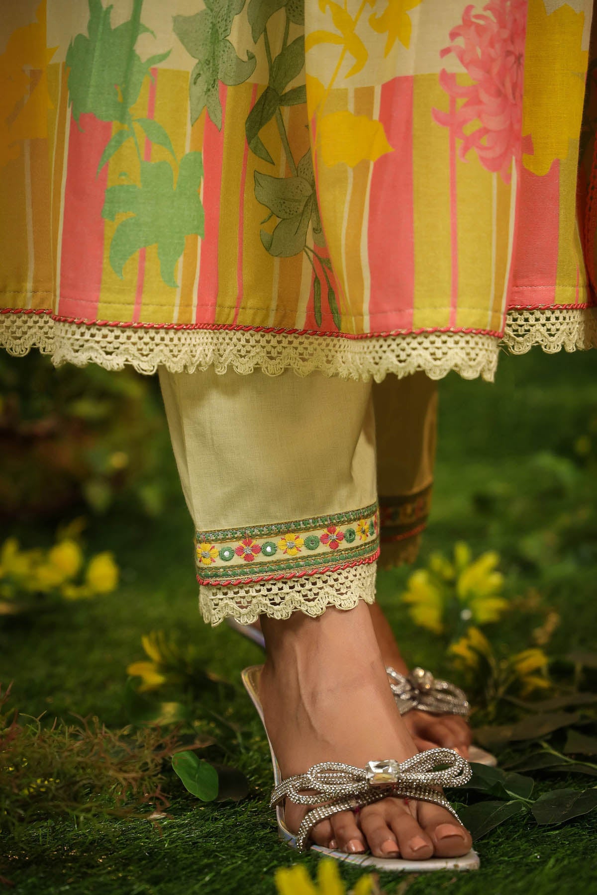 Close-up of a person wearing a colorful skirt and sandals on a grassy background