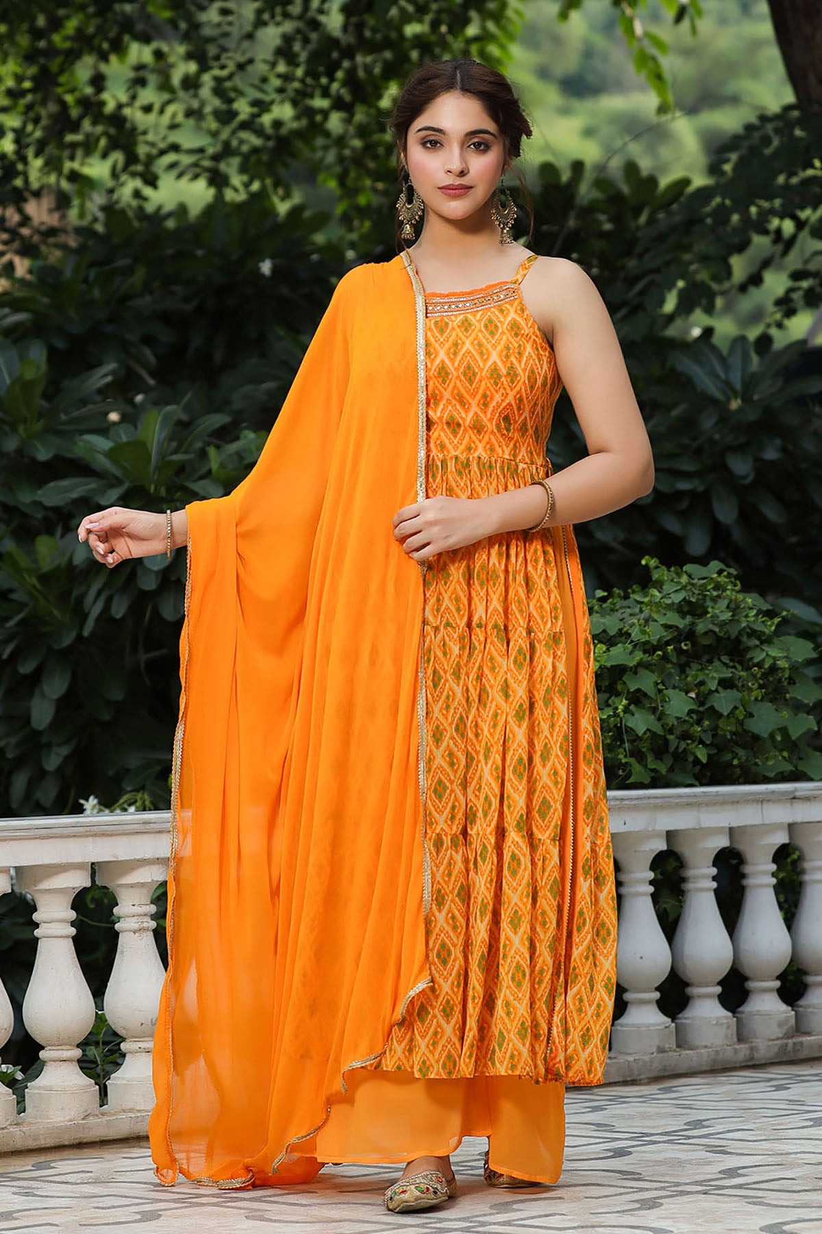 Woman wearing an orange traditional outfit with a matching dupatta in a garden setting