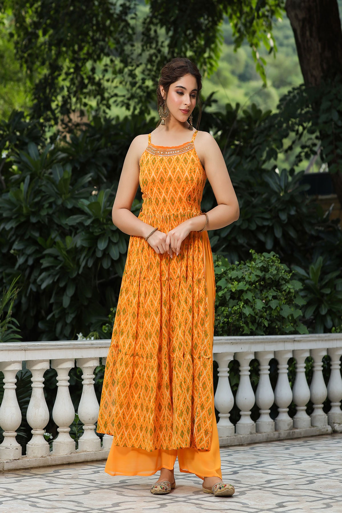 Woman wearing an orange dress with a patterned top and plain bottom, standing outdoors.