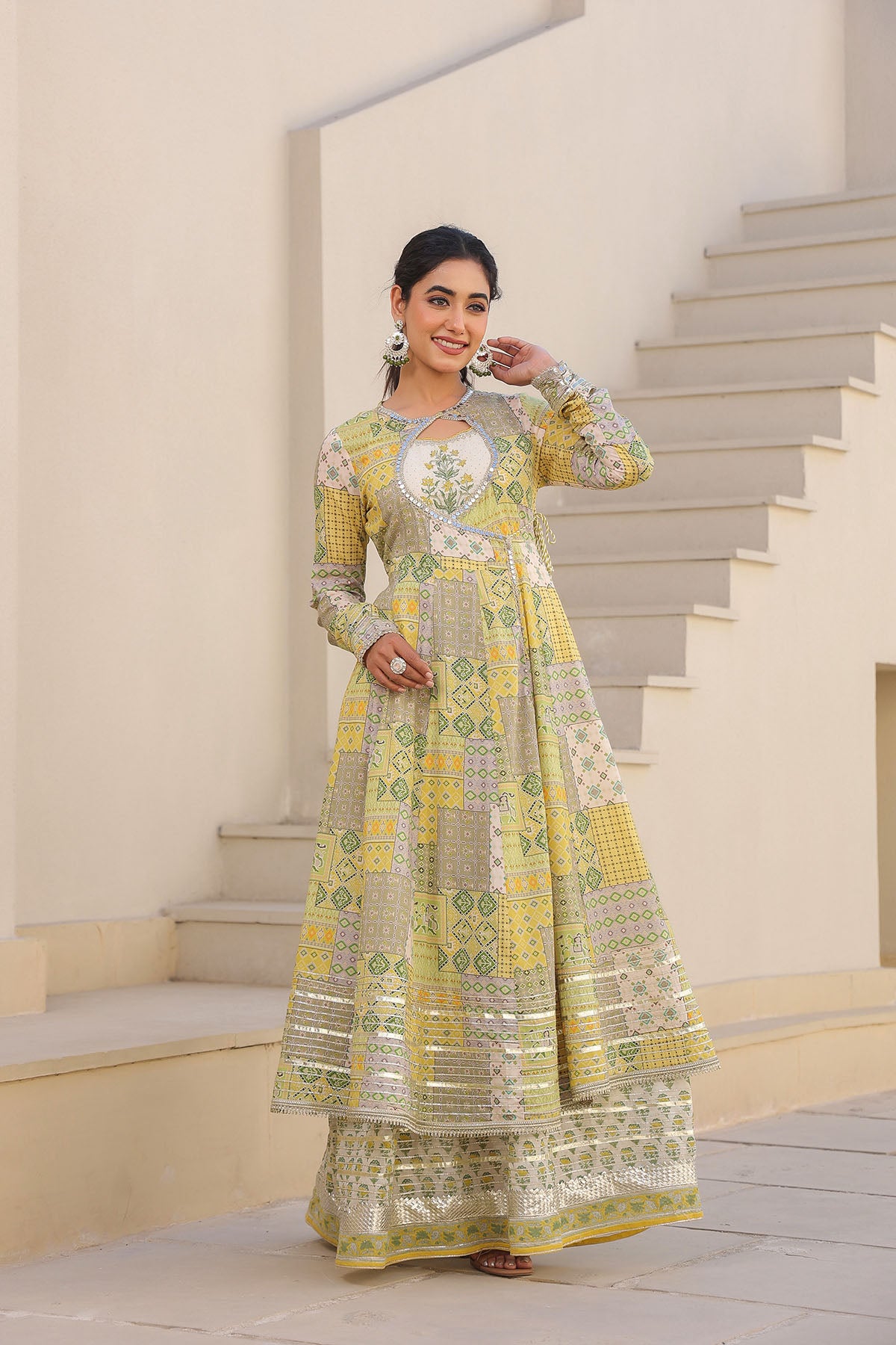 Woman in a yellow and green traditional outfit standing on a staircase.