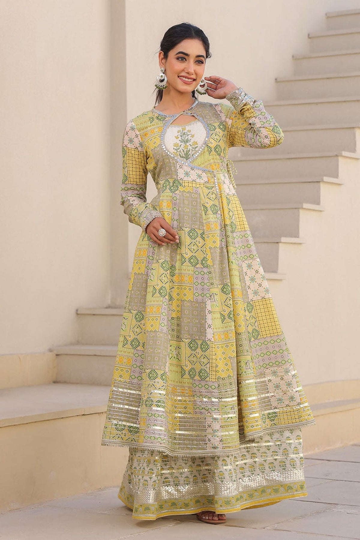Woman in a yellow and green traditional outfit standing on a staircase.