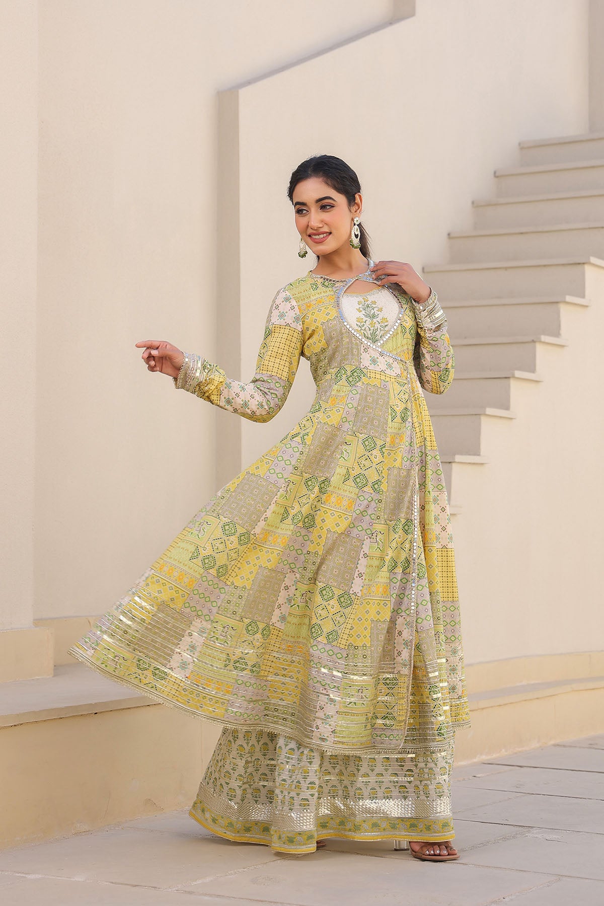 Woman in a yellow and green traditional outfit standing on a staircase.