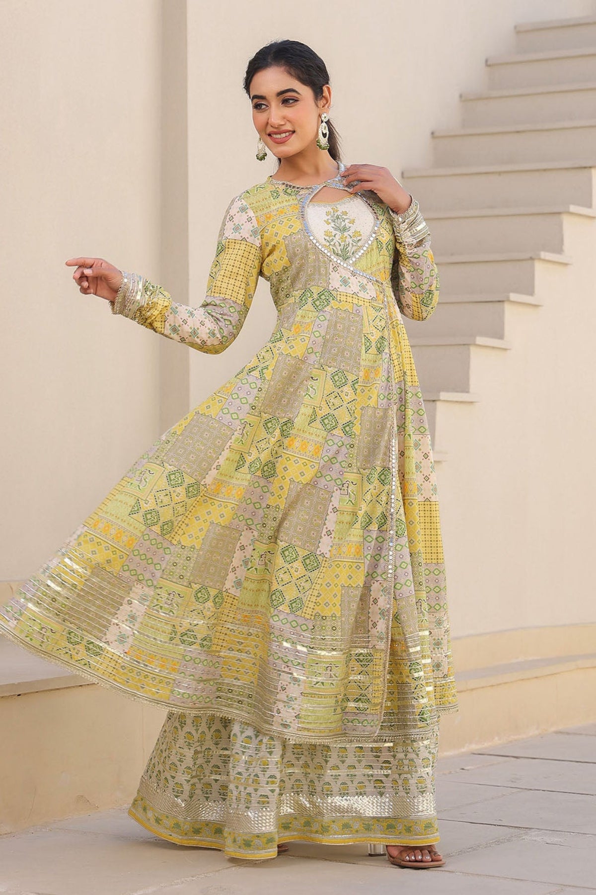 Woman in a yellow and green traditional outfit standing on a staircase.