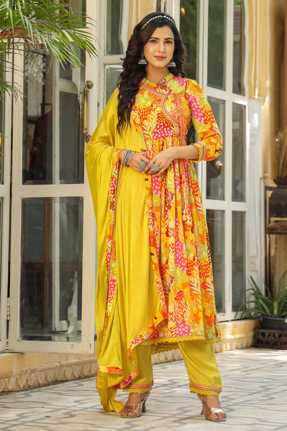Woman in a yellow and floral dress standing outdoors.