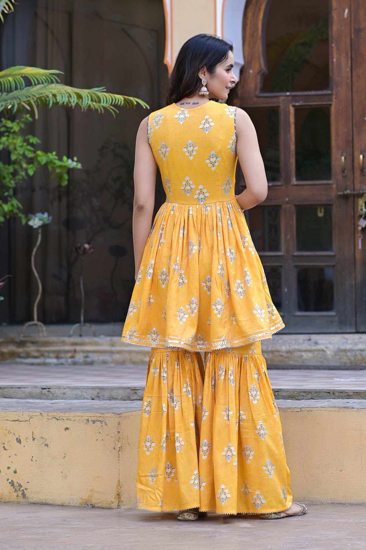 Woman wearing a yellow floral dress standing outdoors.