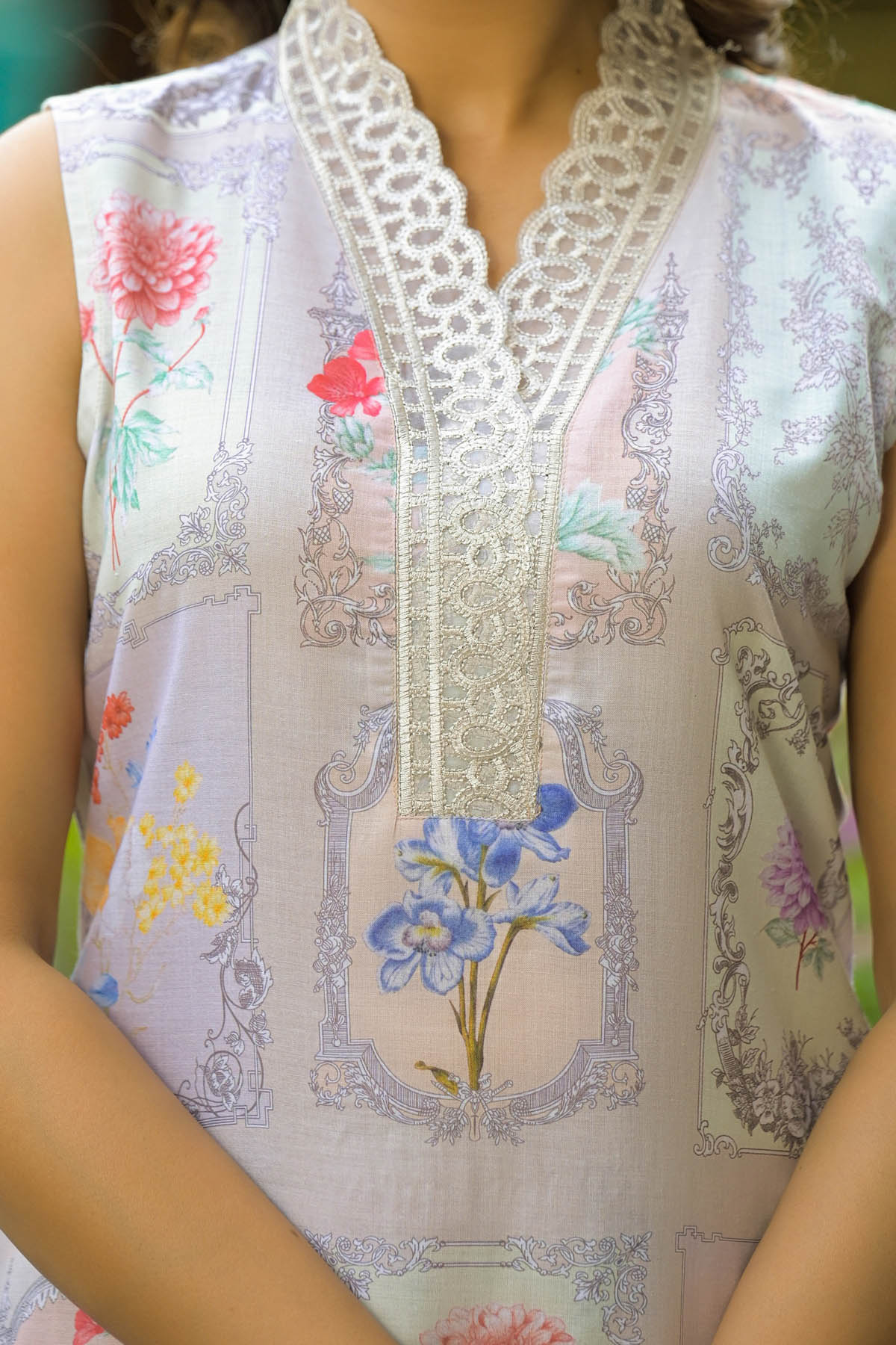 Close-up of a sleeveless top with floral embroidery and lace details.