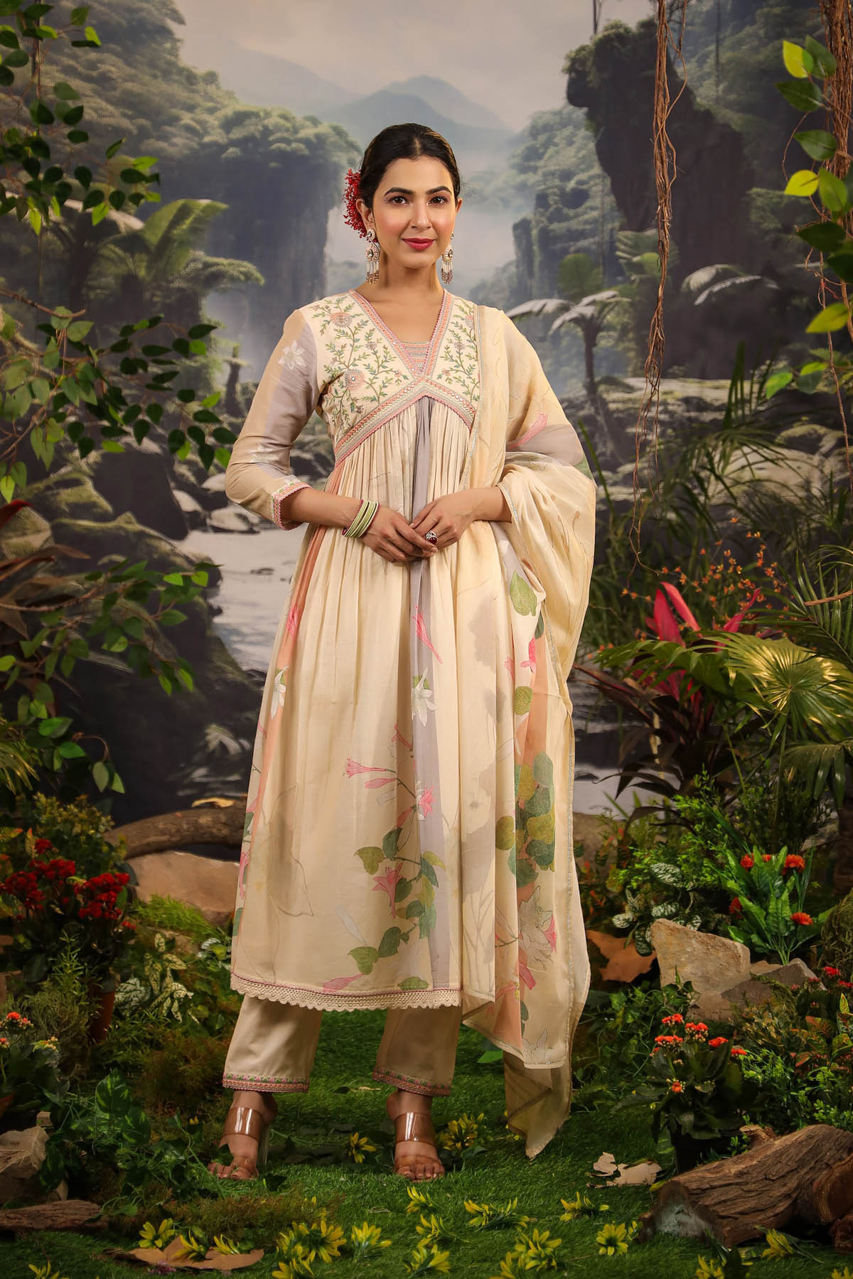 Woman in traditional outfit standing in a natural setting with mountains and plants.