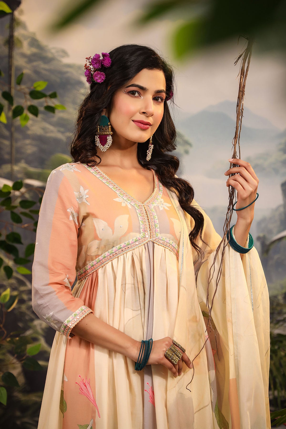 Woman in traditional attire holding a plant with a natural background