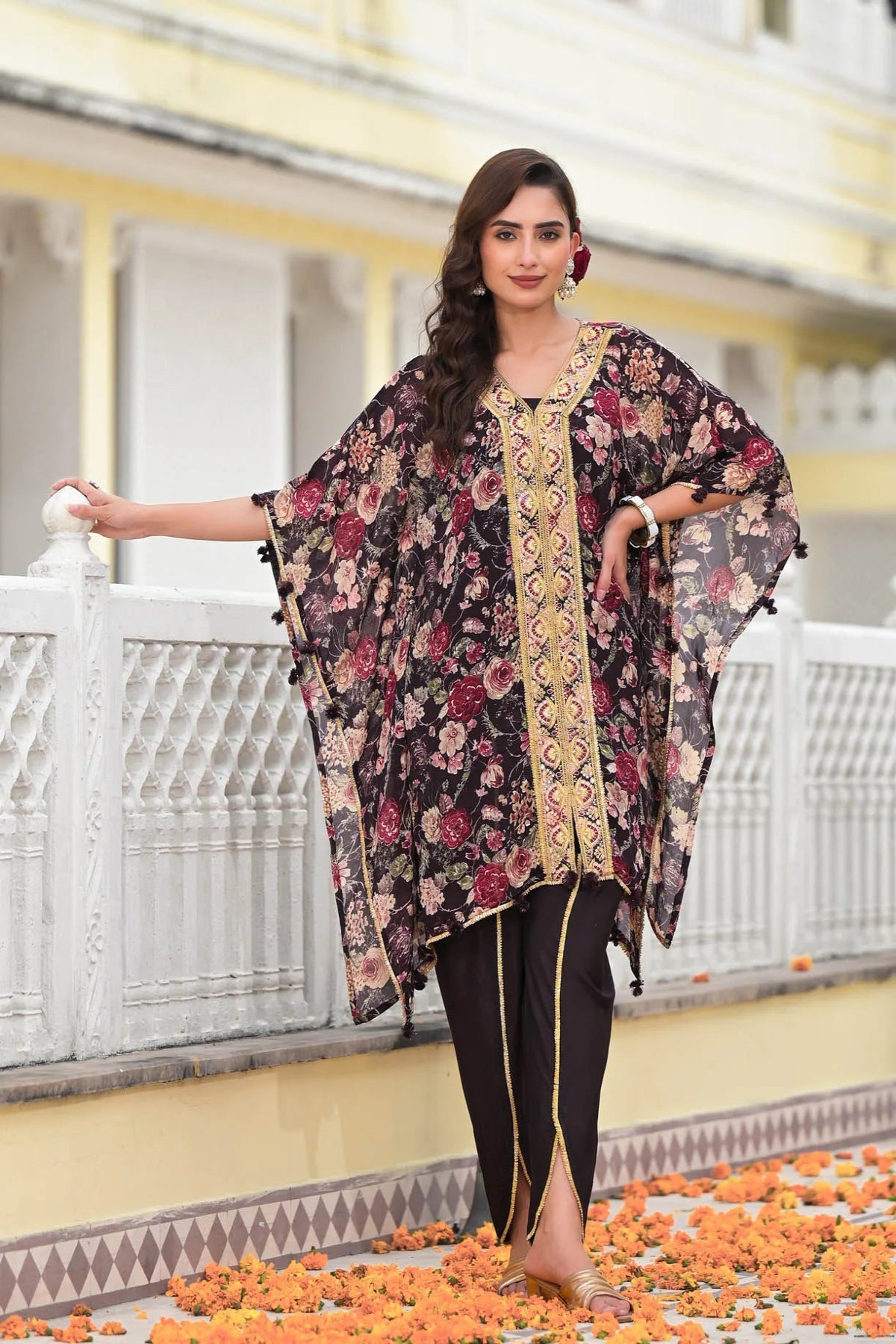 Woman wearing a floral kimono-style outfit standing on a decorative path with flowers.