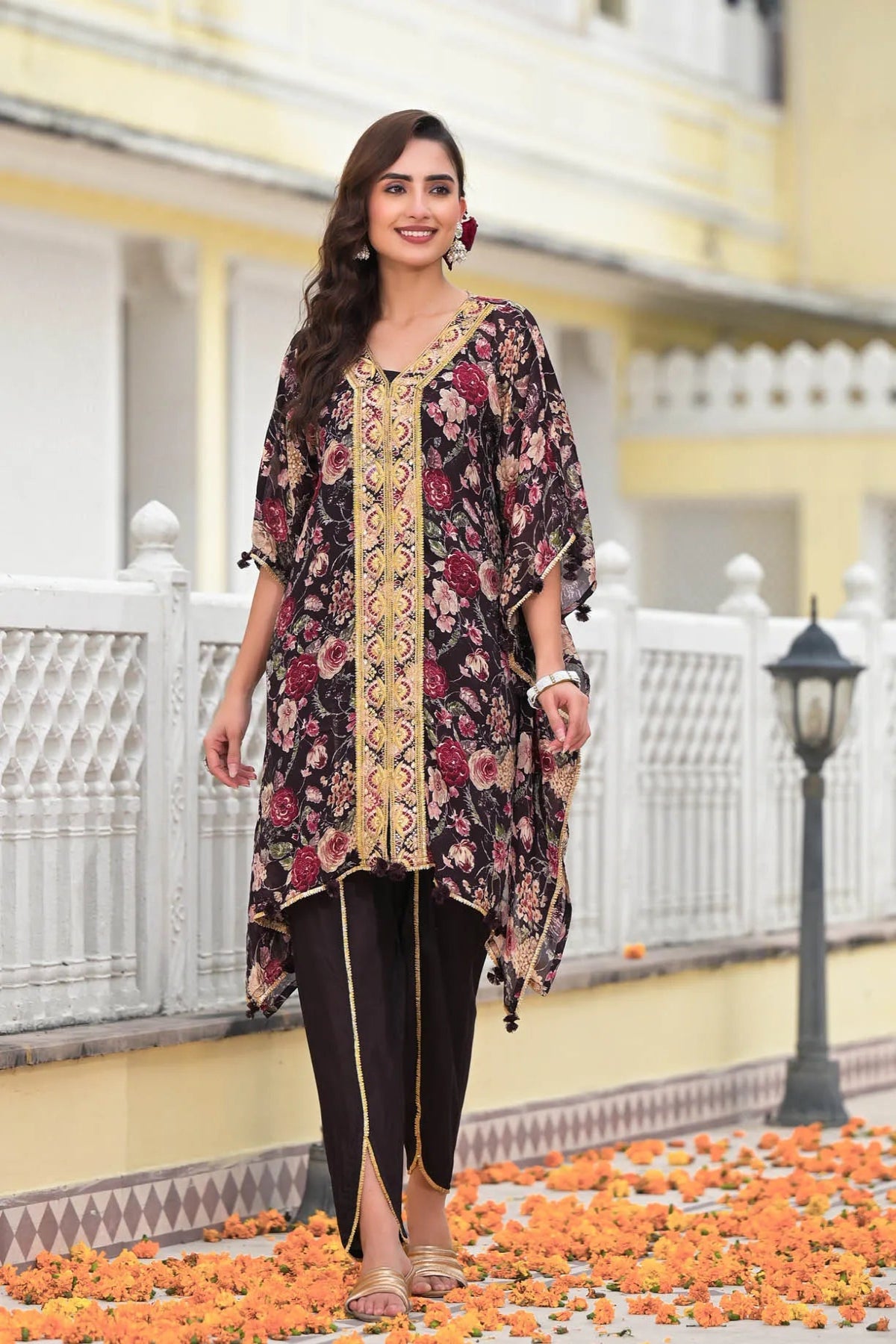 Woman in a floral and embroidered outfit standing on a decorated pathway.