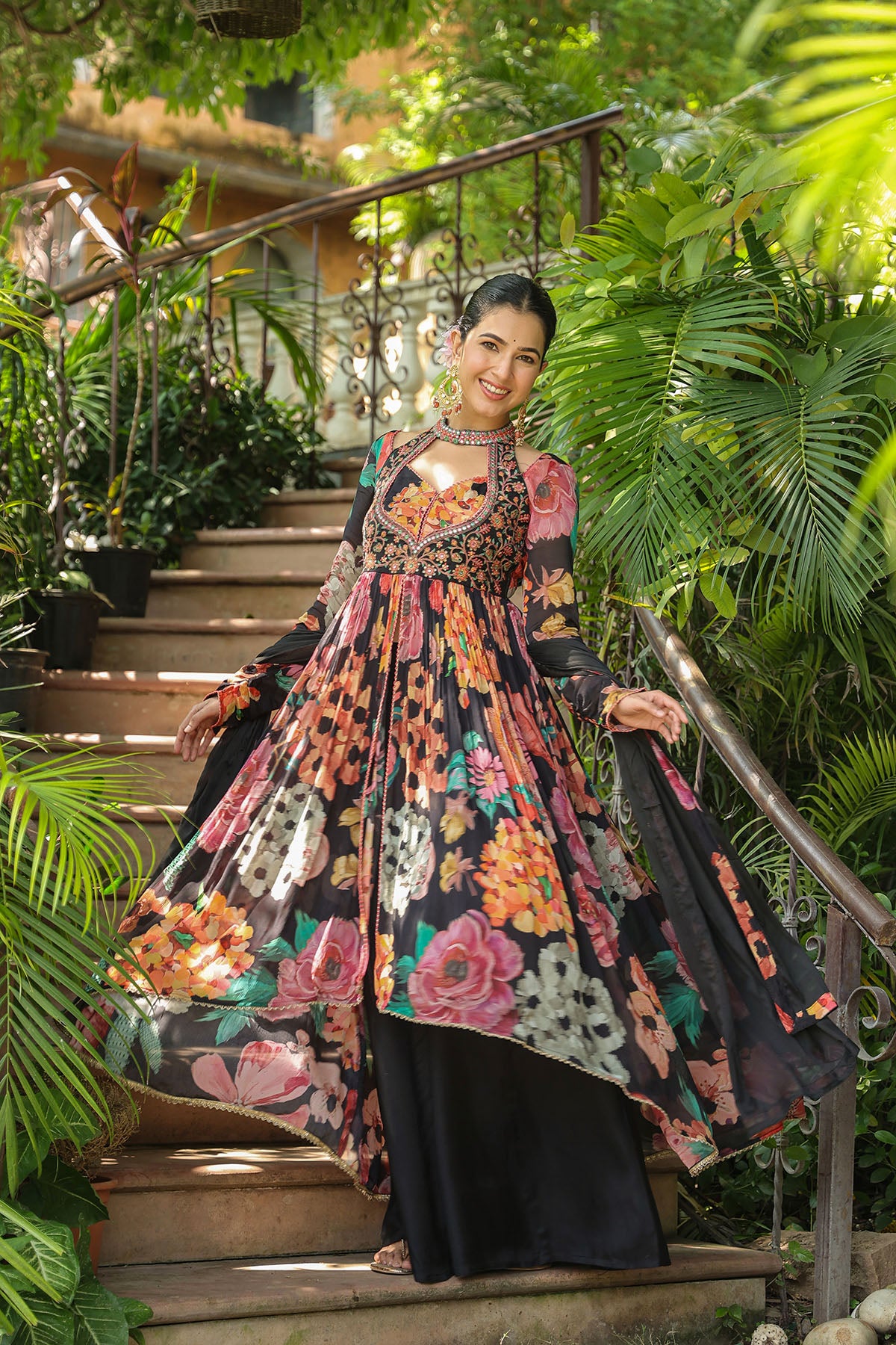 Woman in a floral dress standing on outdoor steps surrounded by greenery