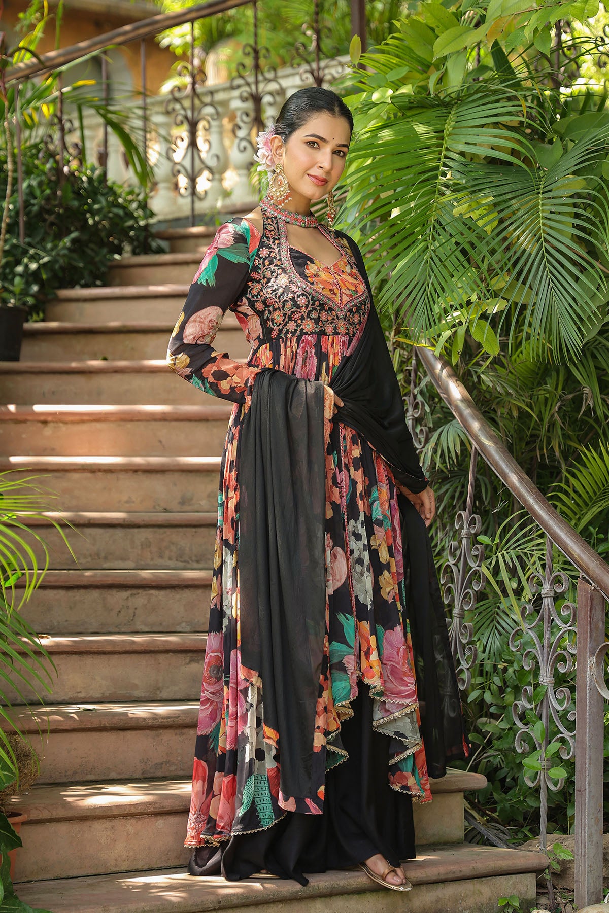 Woman in a floral dress standing on a staircase with greenery around
