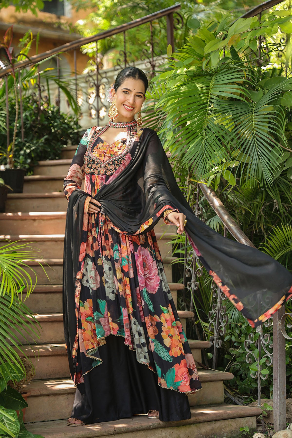 Woman in a floral dress standing on outdoor steps with greenery around
