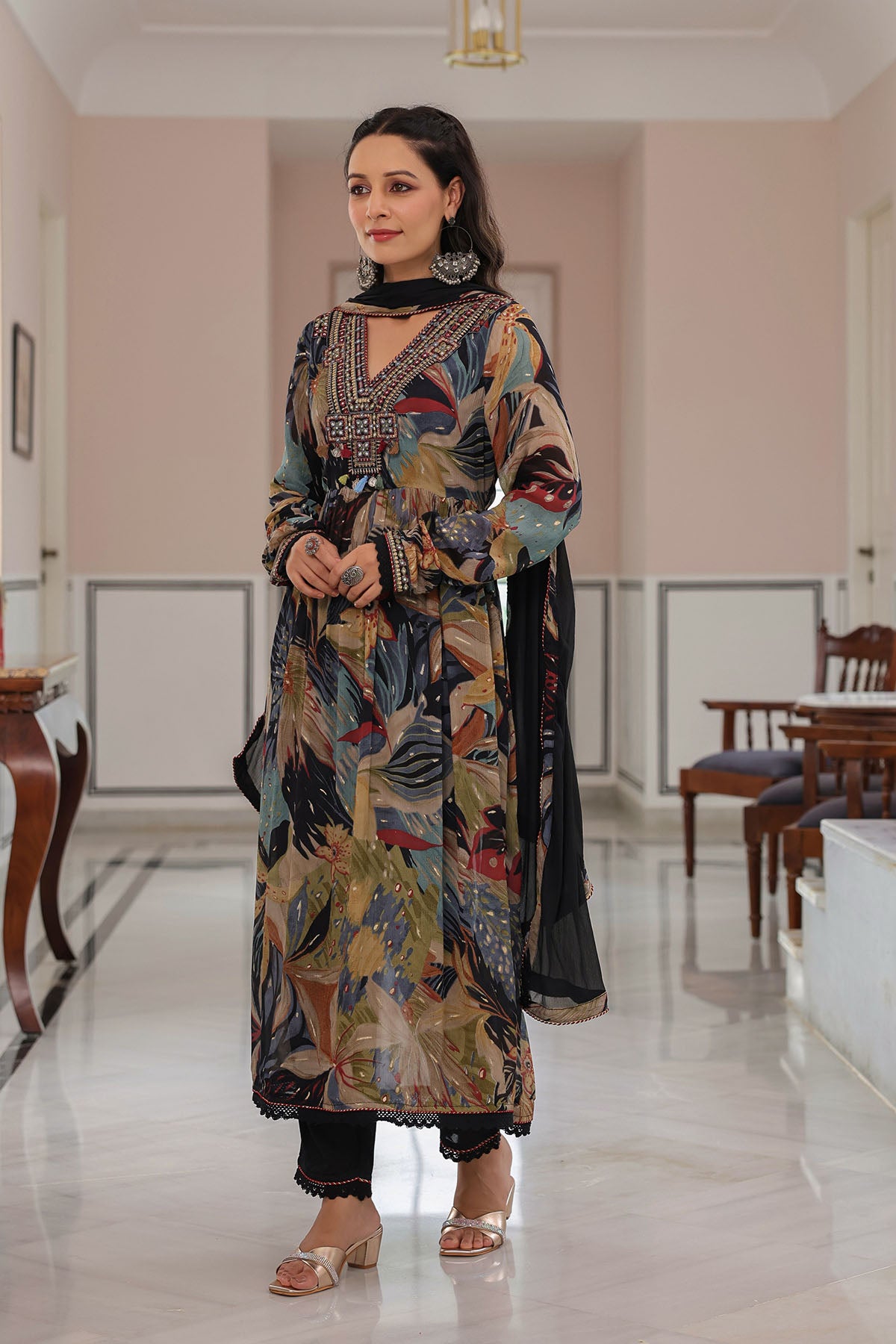 Woman in a colorful traditional outfit standing in a decorated room.