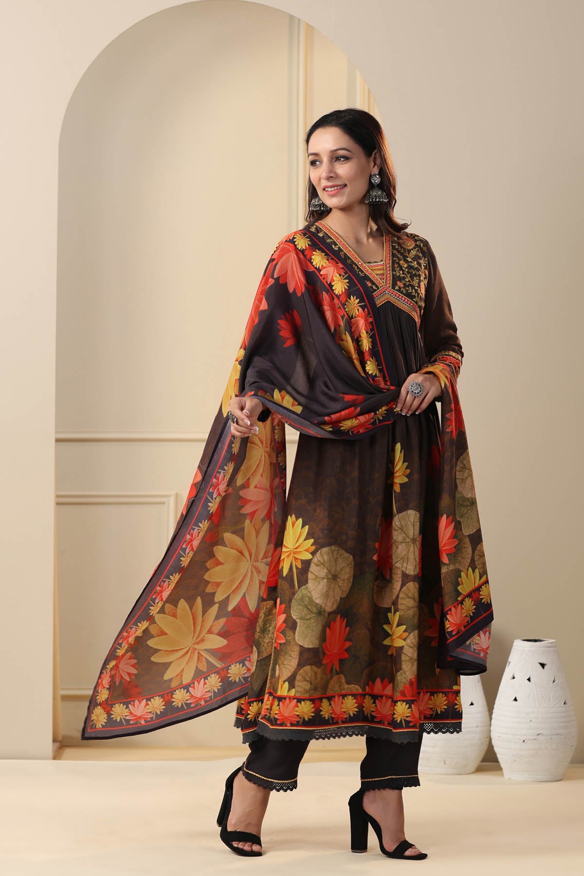 Woman wearing a traditional outfit with floral patterns in a neutral setting