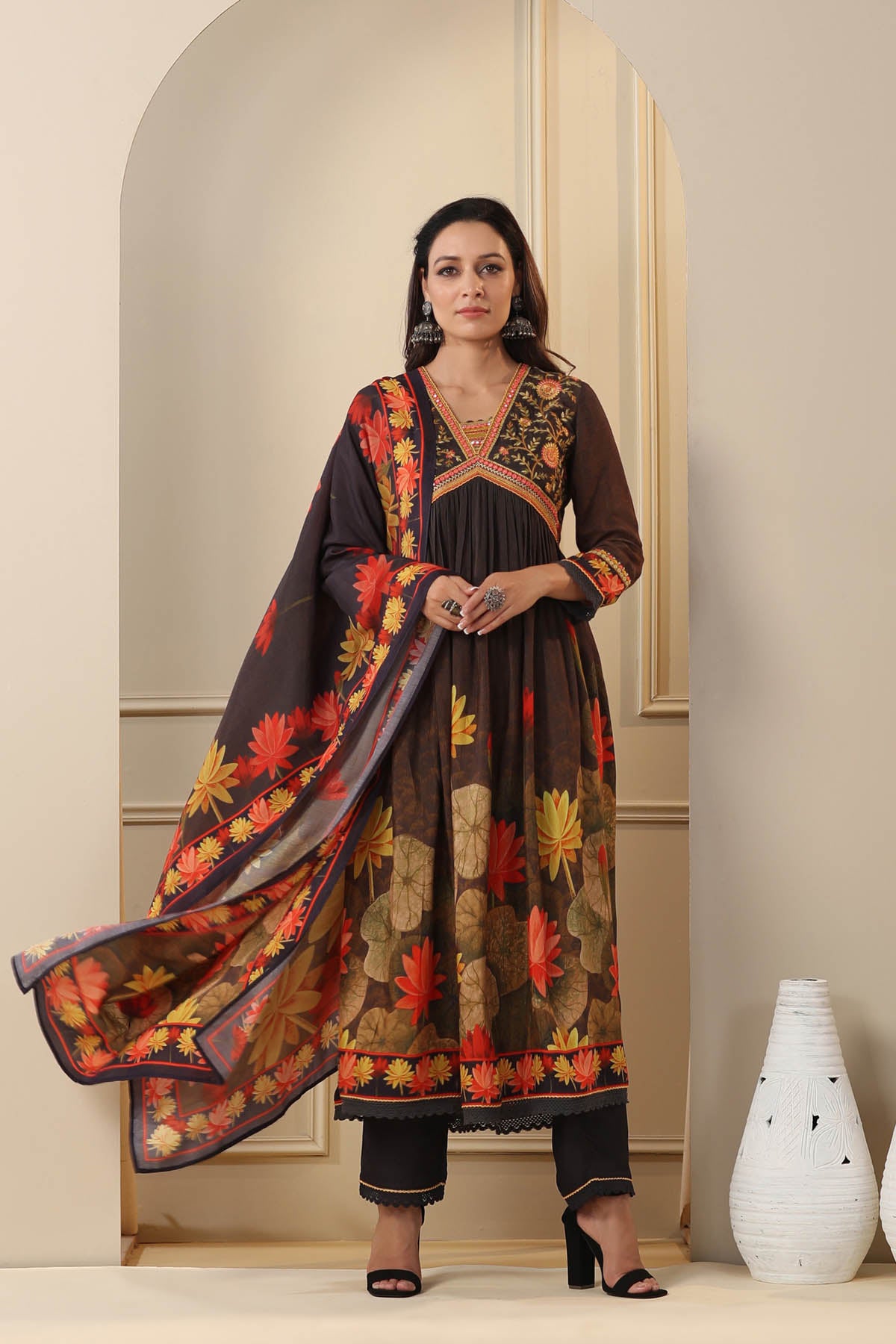 Woman wearing a traditional outfit with floral patterns in a neutral setting