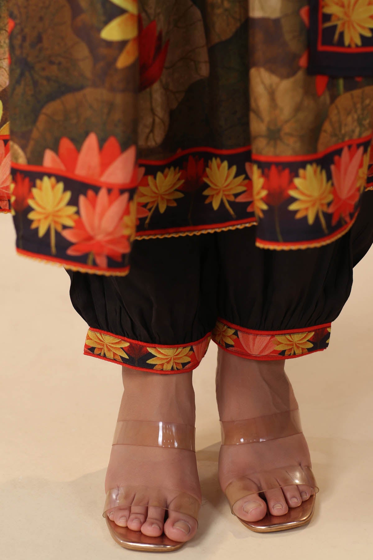 Traditional outfit with floral patterns and transparent sandals on a beige background