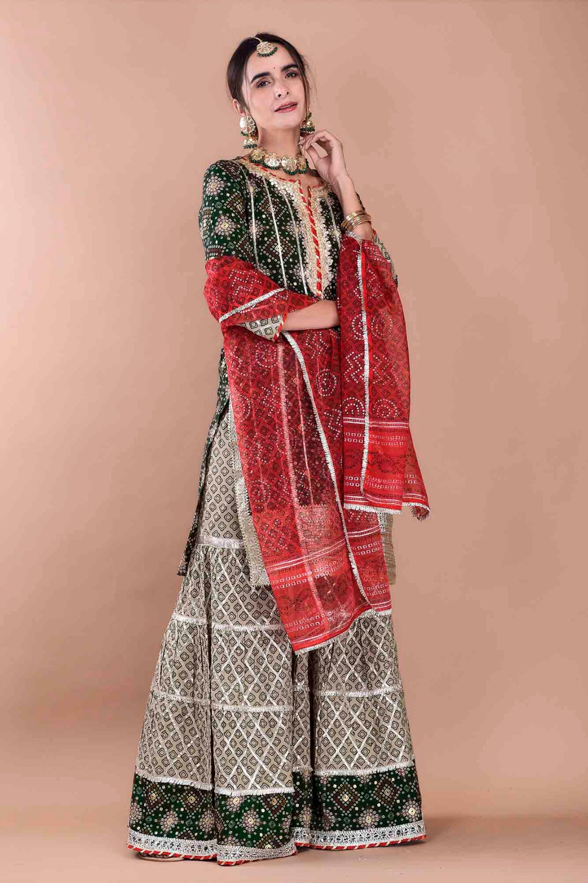 Woman wearing a traditional outfit with a red and white patterned dupatta on a beige background