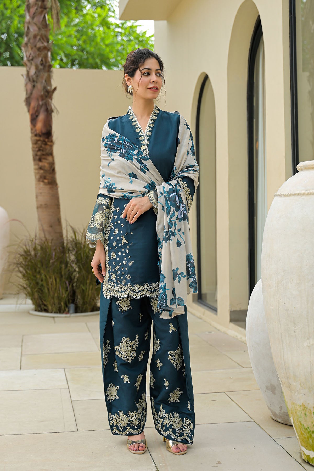 Woman in a blue and white traditional outfit standing outdoors.