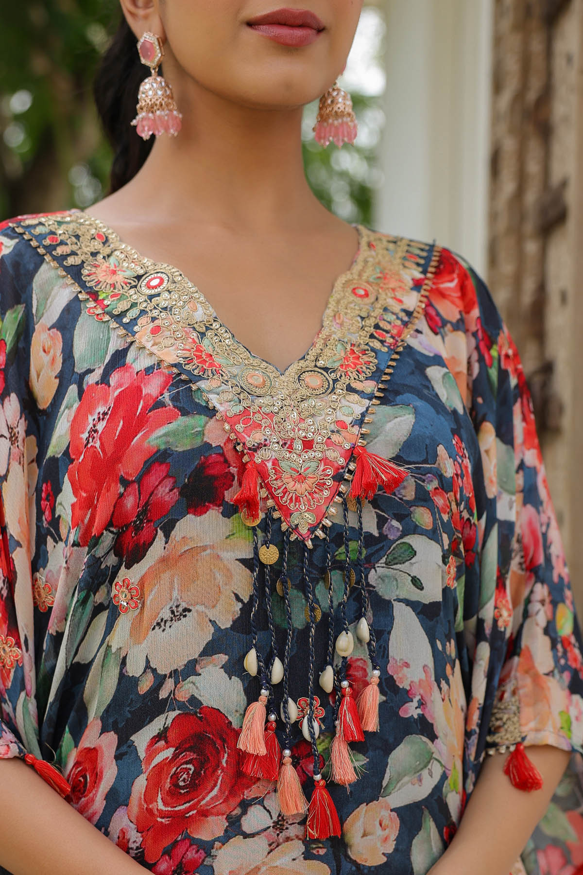 Woman wearing a floral dress with intricate embroidery and jewelry.