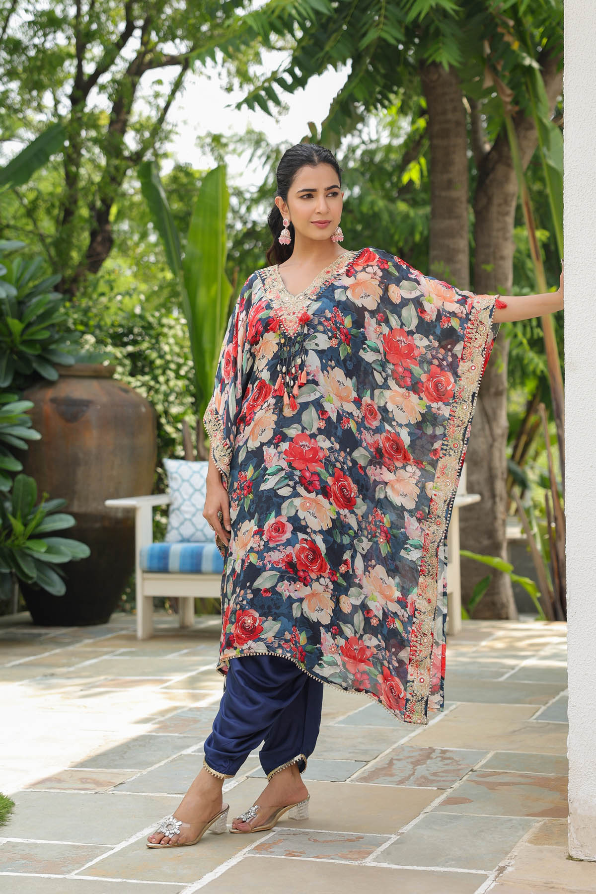 Woman wearing a floral dress standing outdoors with greenery in the background