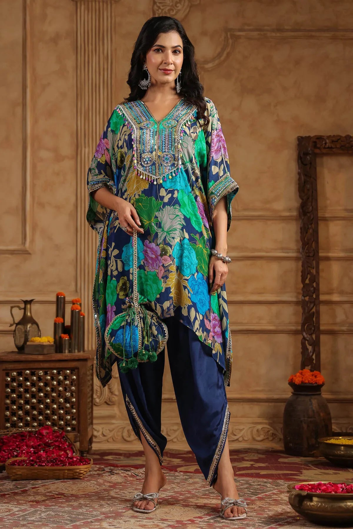 Woman wearing a colorful traditional outfit with a floral pattern in an ornate room.