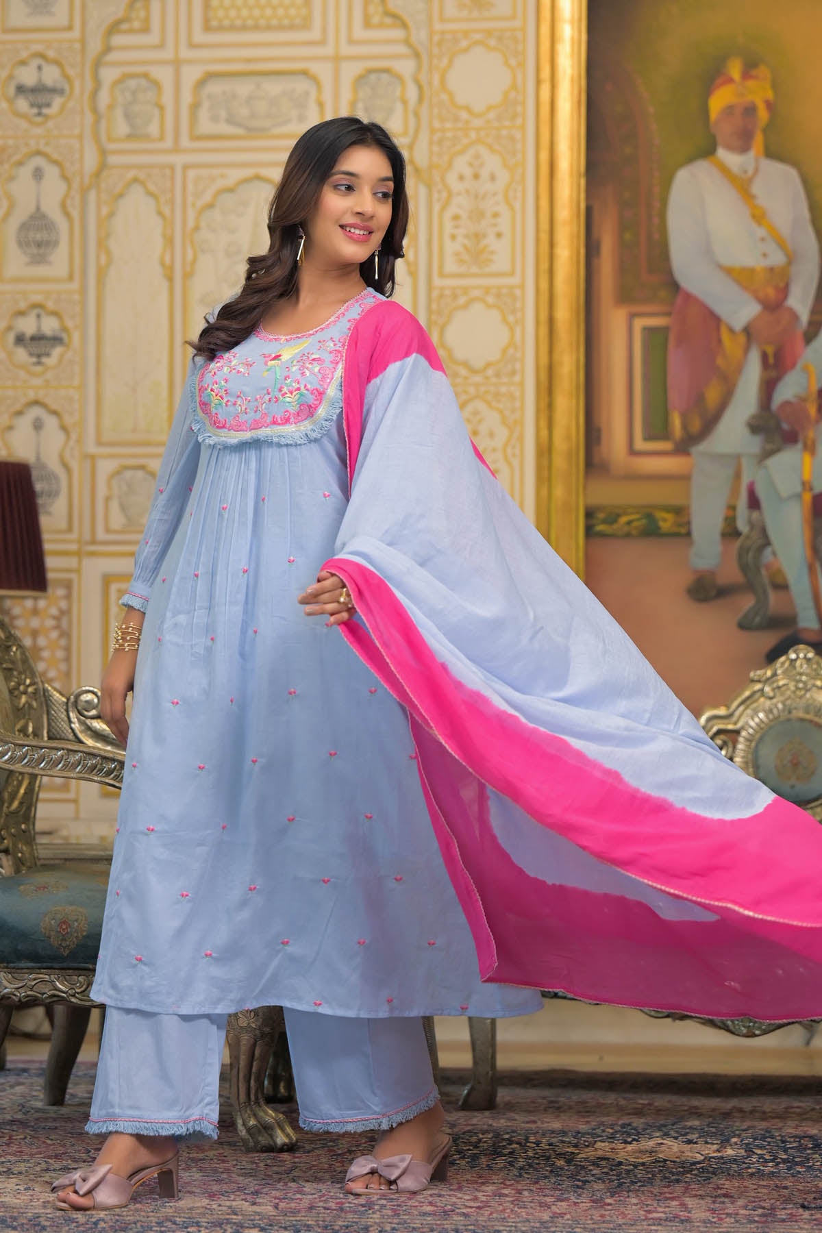 Woman in traditional outfit with pink dupatta in ornate room