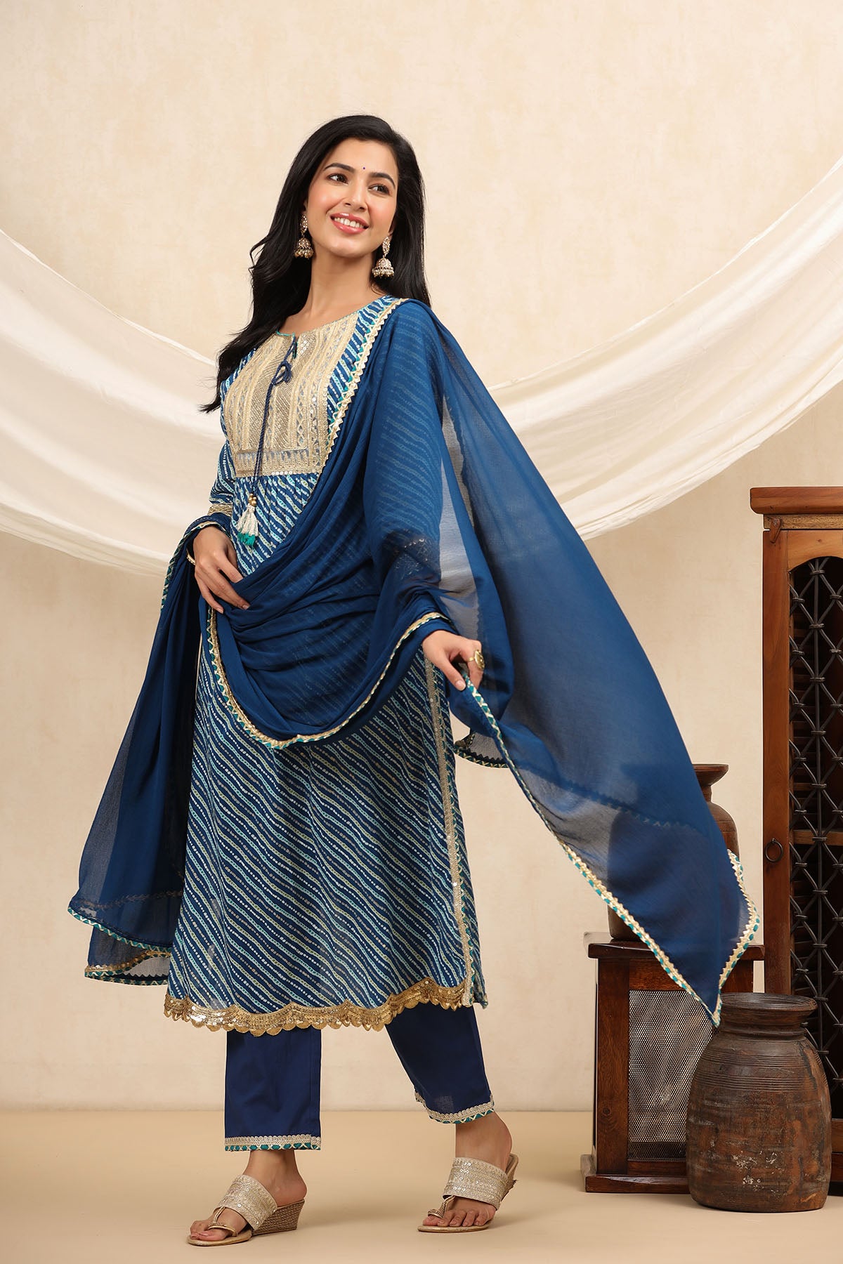 Woman wearing a blue traditional outfit with a dupatta in a neutral setting