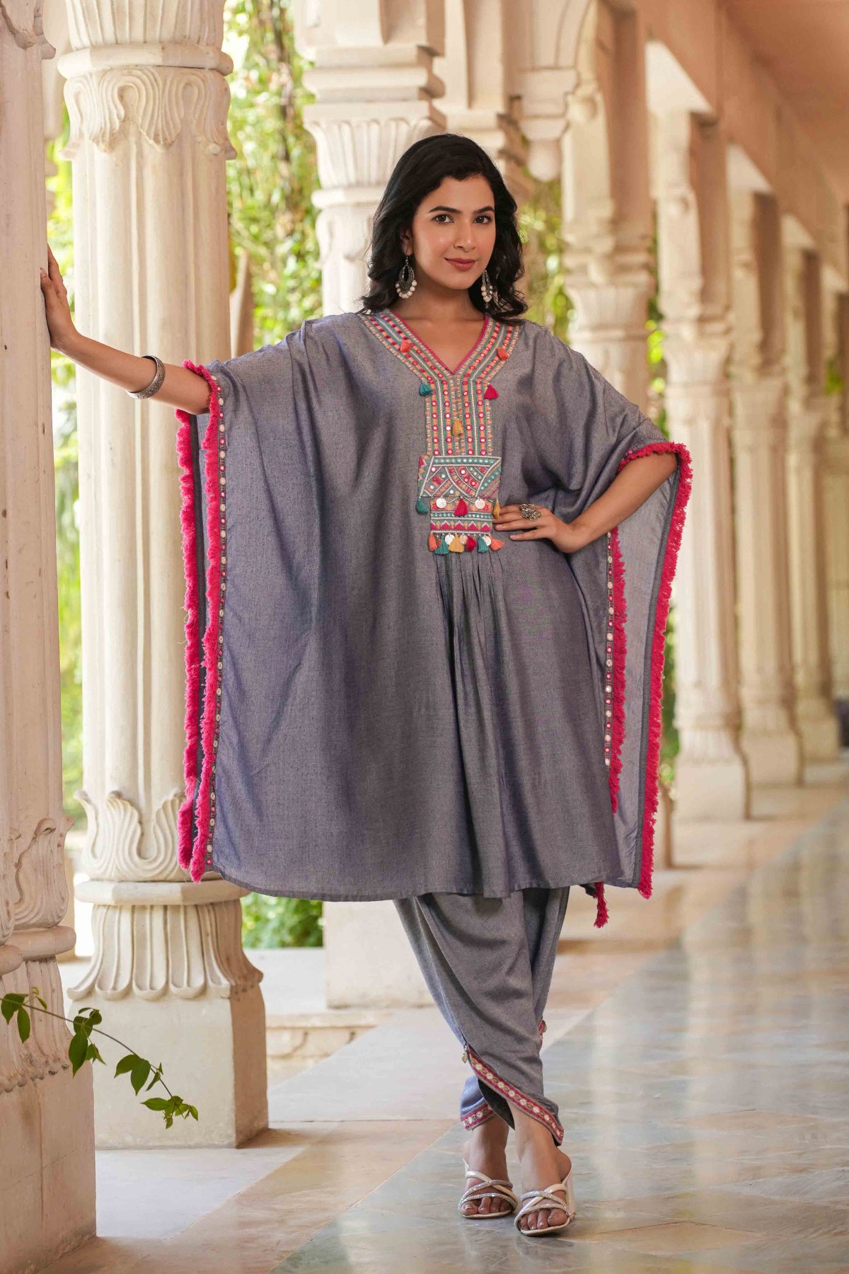 Woman wearing a traditional outfit with intricate designs in an outdoor setting.