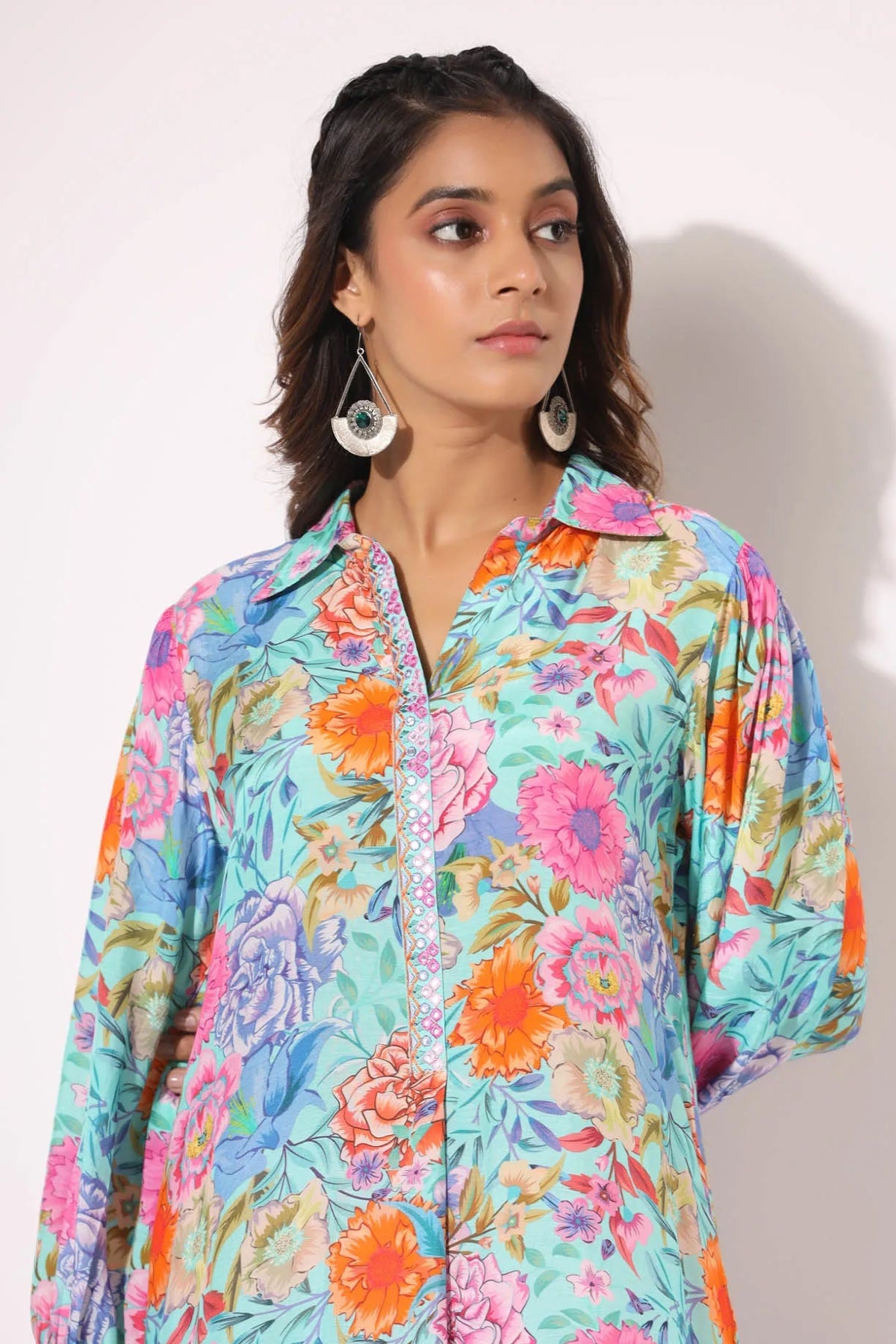 Woman wearing a colorful floral shirt against a plain background