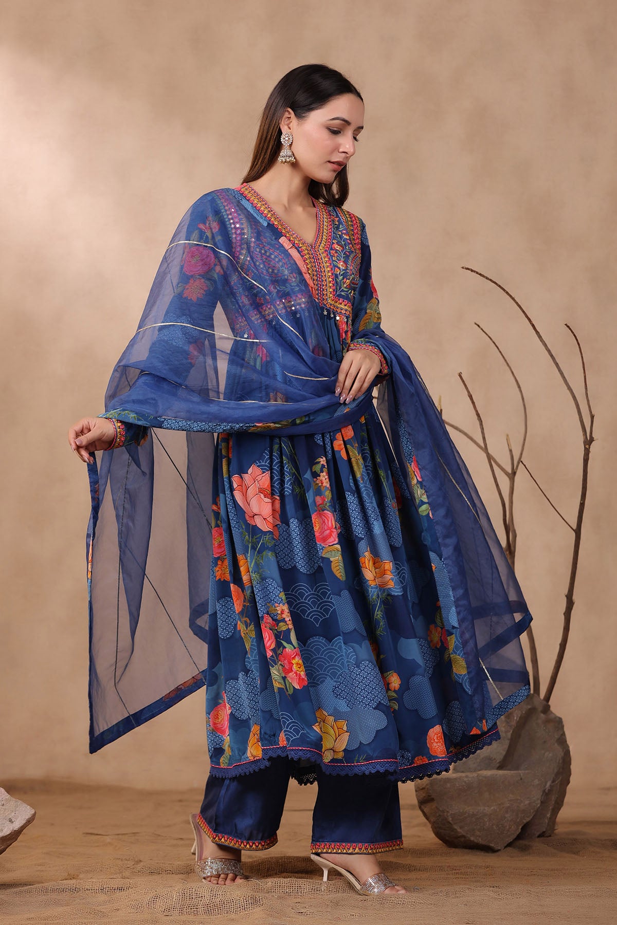 Woman wearing a blue floral traditional outfit against a beige background