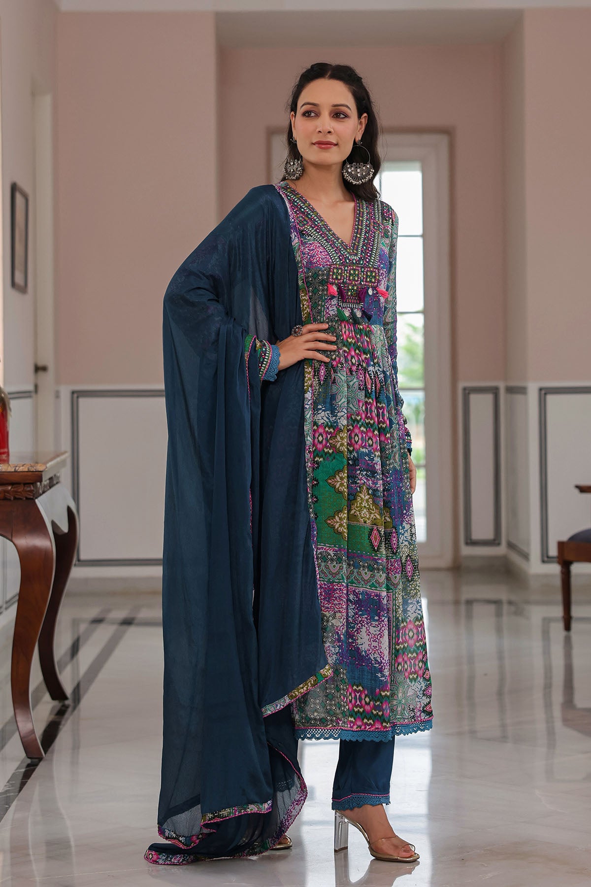 Woman in a colorful traditional outfit standing in a well-lit room.