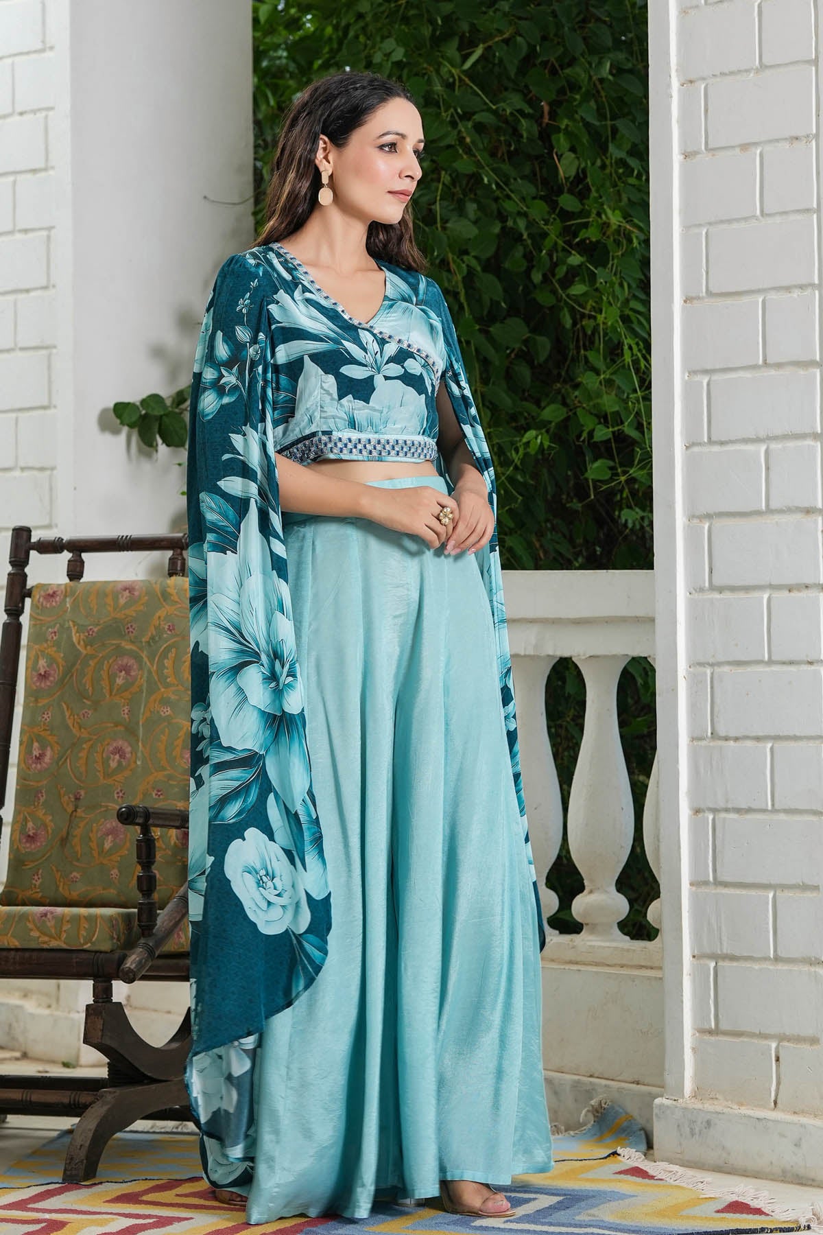 Woman wearing a teal floral dress with a matching shawl on a porch.