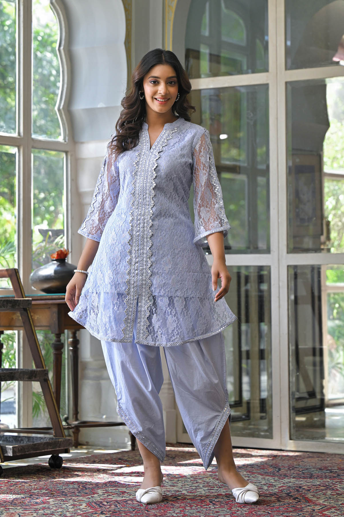 Woman wearing a light blue traditional outfit with lace details indoors.